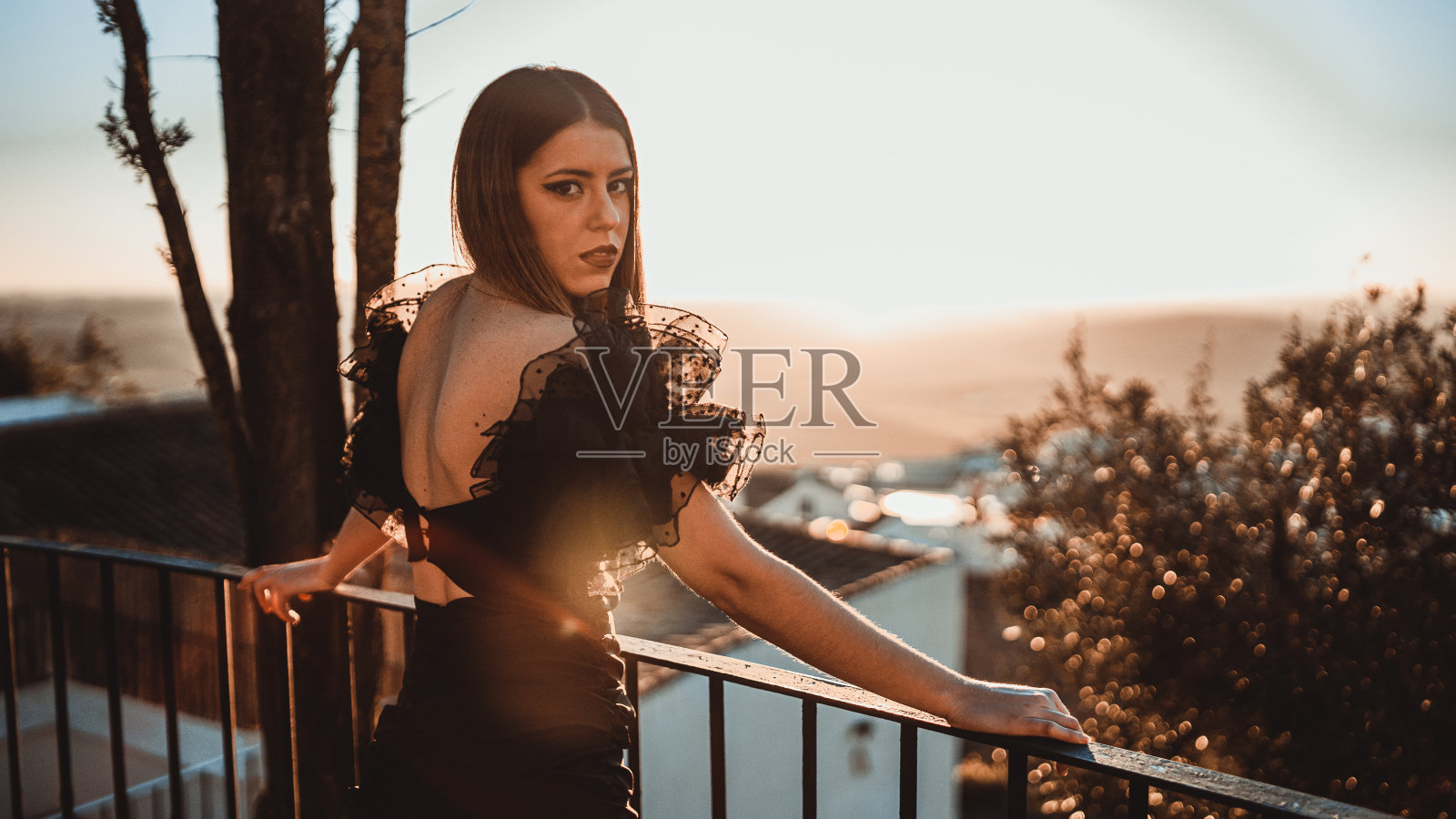 浅聚焦镜头的一个美丽的女人穿着黑色在阳台上日落照片摄影图片