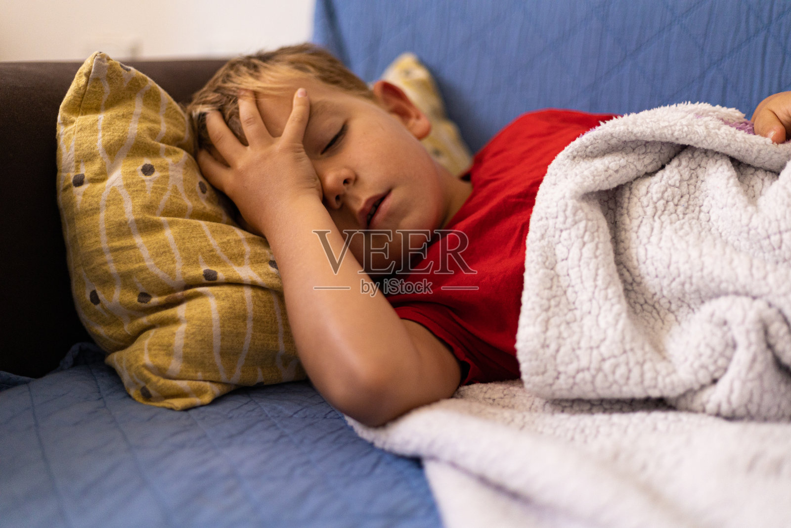 不健康的小男孩用温度计测量体温，在床上睡觉，在家里客厅放松照片摄影图片