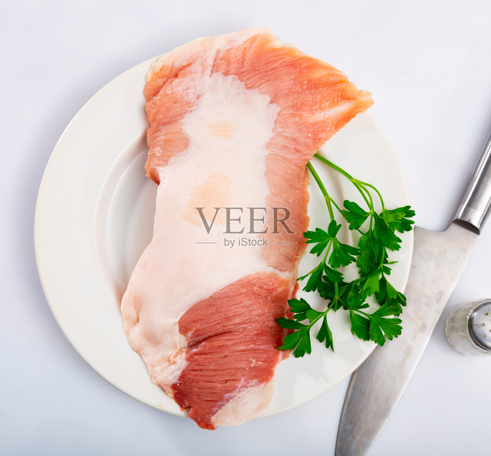生肉，猪肉排加香料放在白色盘子里照片摄影图片