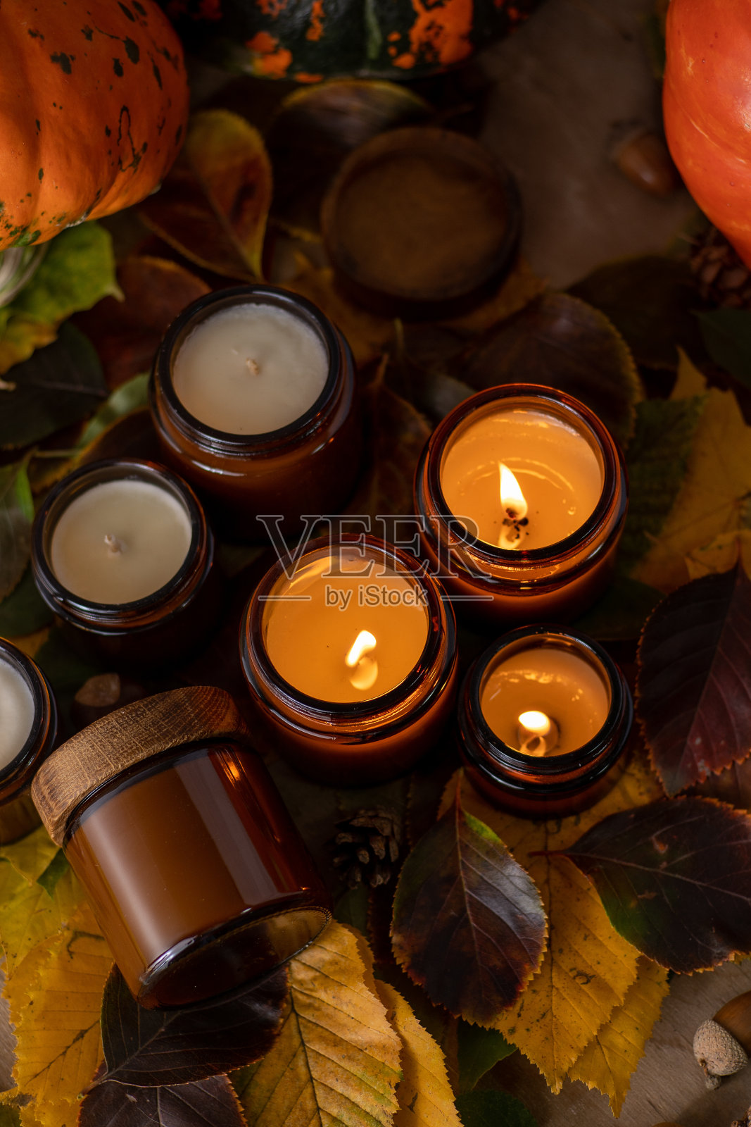 大豆蜡烛在玻璃罐中燃烧。树的叶子。家里舒适。棕色罐子里的蜡烛。光和气味。有香味的手工蜡烛。芳香疗法。秋天的心情。秋天舒适的家居装饰。节日装饰照片摄影图片