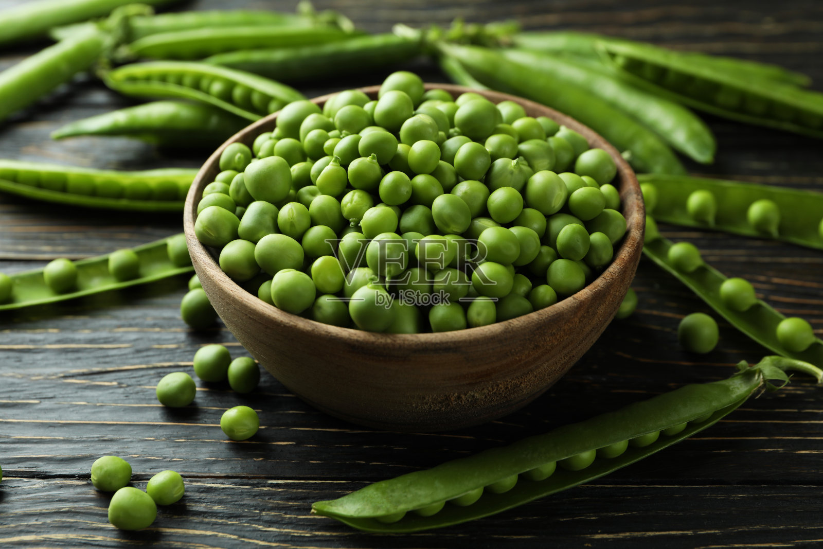 碗与新鲜的豌豆种子在木制背景照片摄影图片