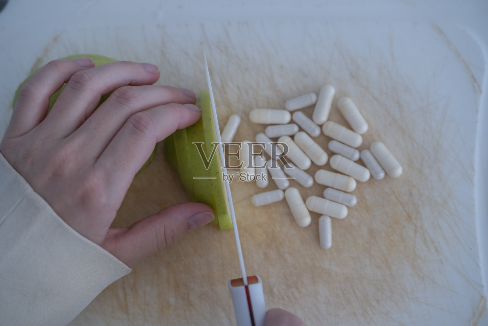 女孩用刀切一个青苹果，维生素出现了。蔬菜和水果中的维生素。健康饮食。照片摄影图片