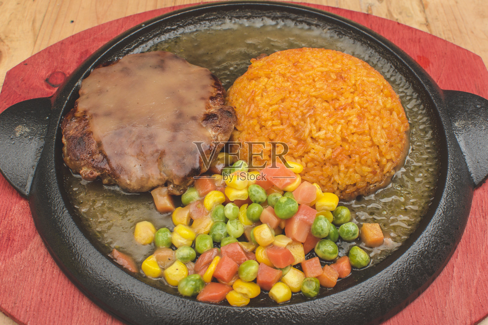 索尔兹伯里牛排，配上混合蔬菜和炒爪哇饭，放在滋滋作响的盘子里，配上肉汁。照片摄影图片