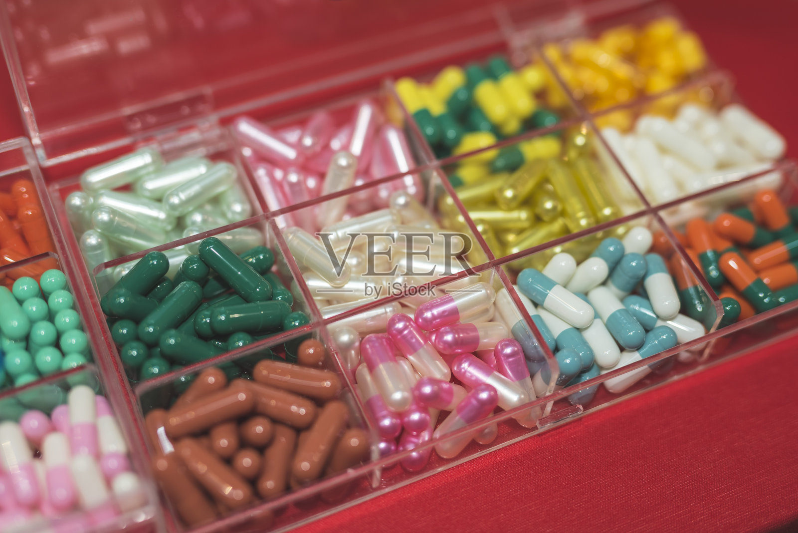 博览会上，一家制造商在一个有组织的盒子里展示各种不同颜色的硬壳明胶胶囊。照片摄影图片