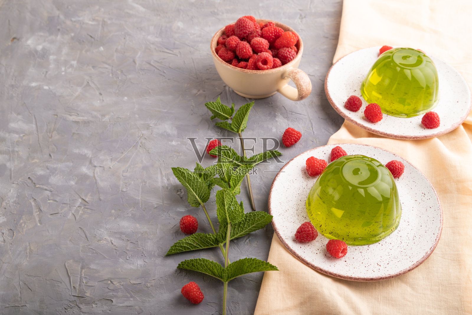 薄荷和覆盆子绿色果冻灰色混凝土和橙色亚麻纺织品。侧视图，复制空间。照片摄影图片