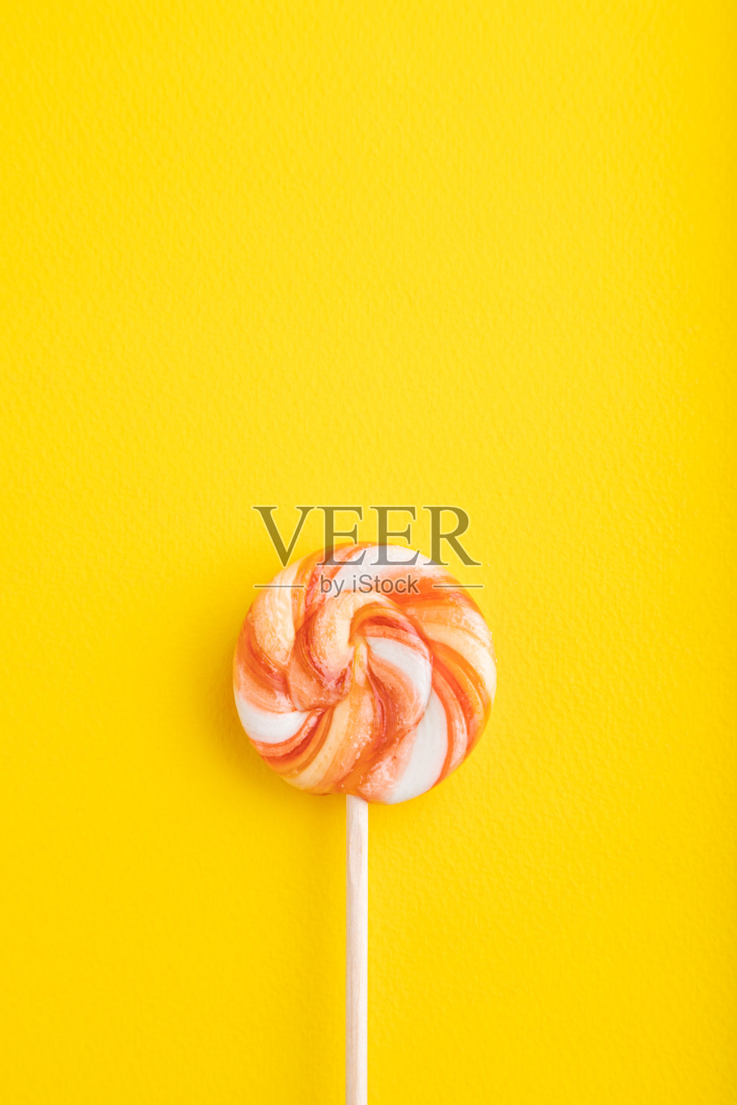 黄色背景上的单一棒棒糖。复制空间，俯视图照片摄影图片