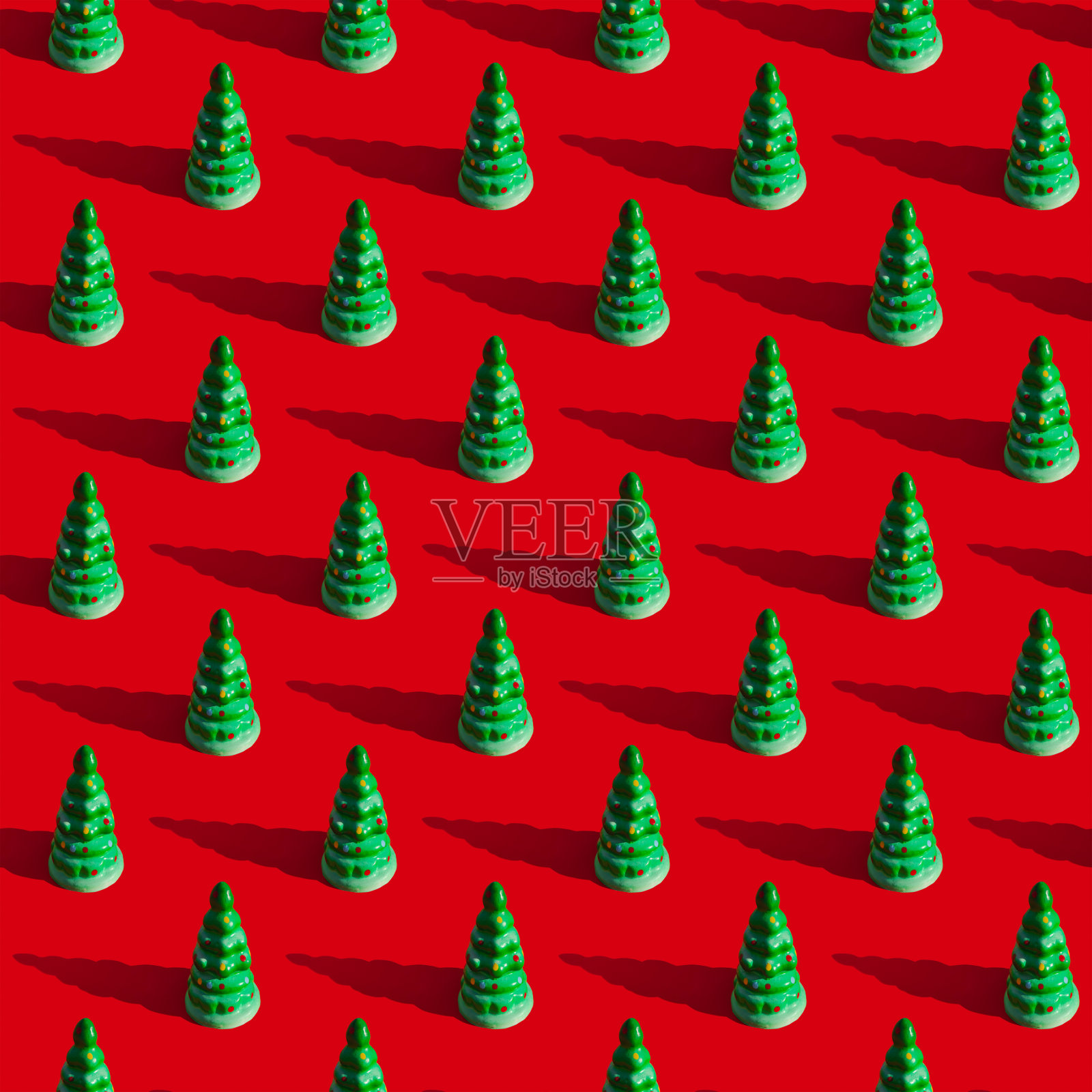 重复的图案从绿色玩具圣诞树与阴影在一个红色的背景。新年和圣诞节的概念照片摄影图片