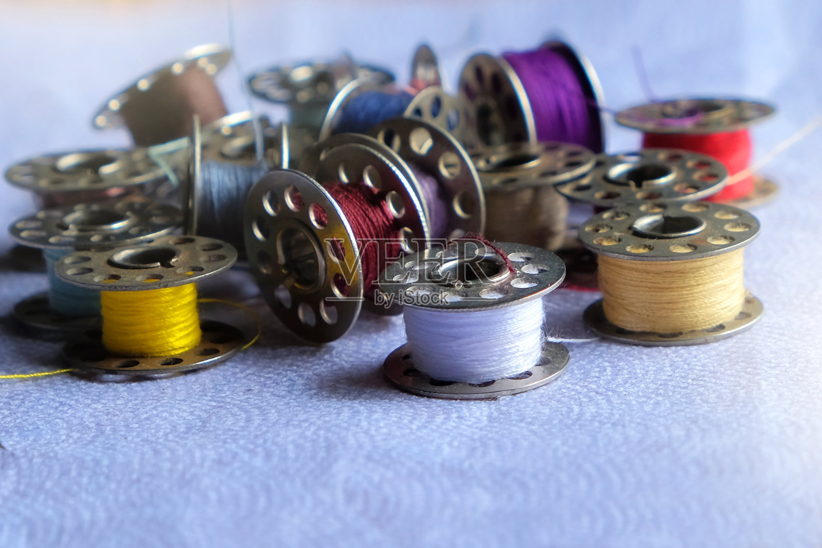 纺线机上的彩色线与其他纺线的模糊背景形成鲜明对比照片摄影图片