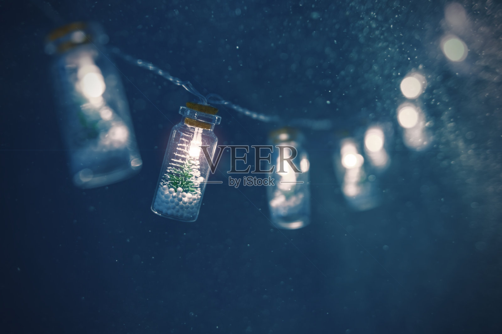 用深蓝色背景的瓶子装着圣诞树的圣诞花环。照片摄影图片