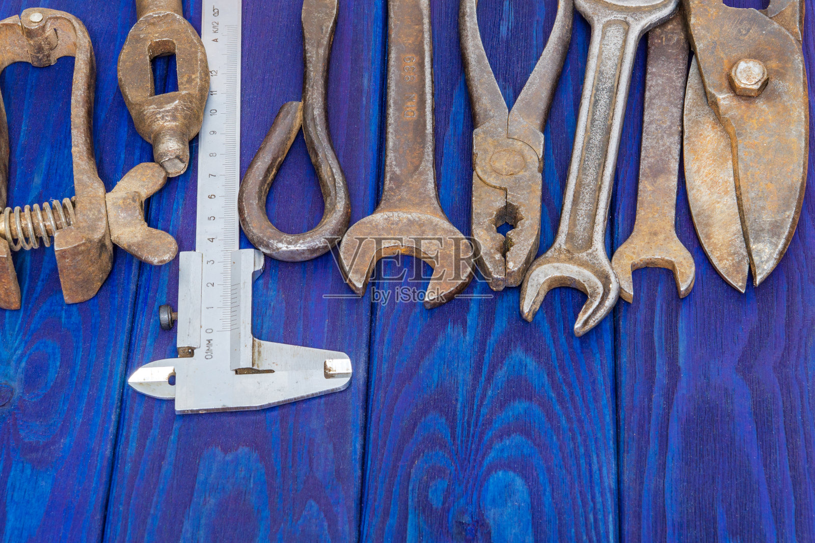 许多古老的工匠工具在工作后堆放在蓝色的木板上照片摄影图片