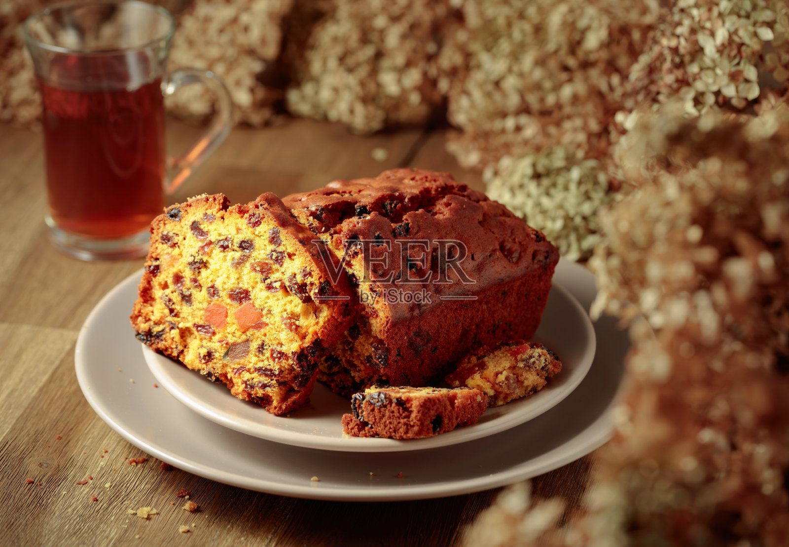 水果蛋糕和茶放在木桌上，还有干花。照片摄影图片