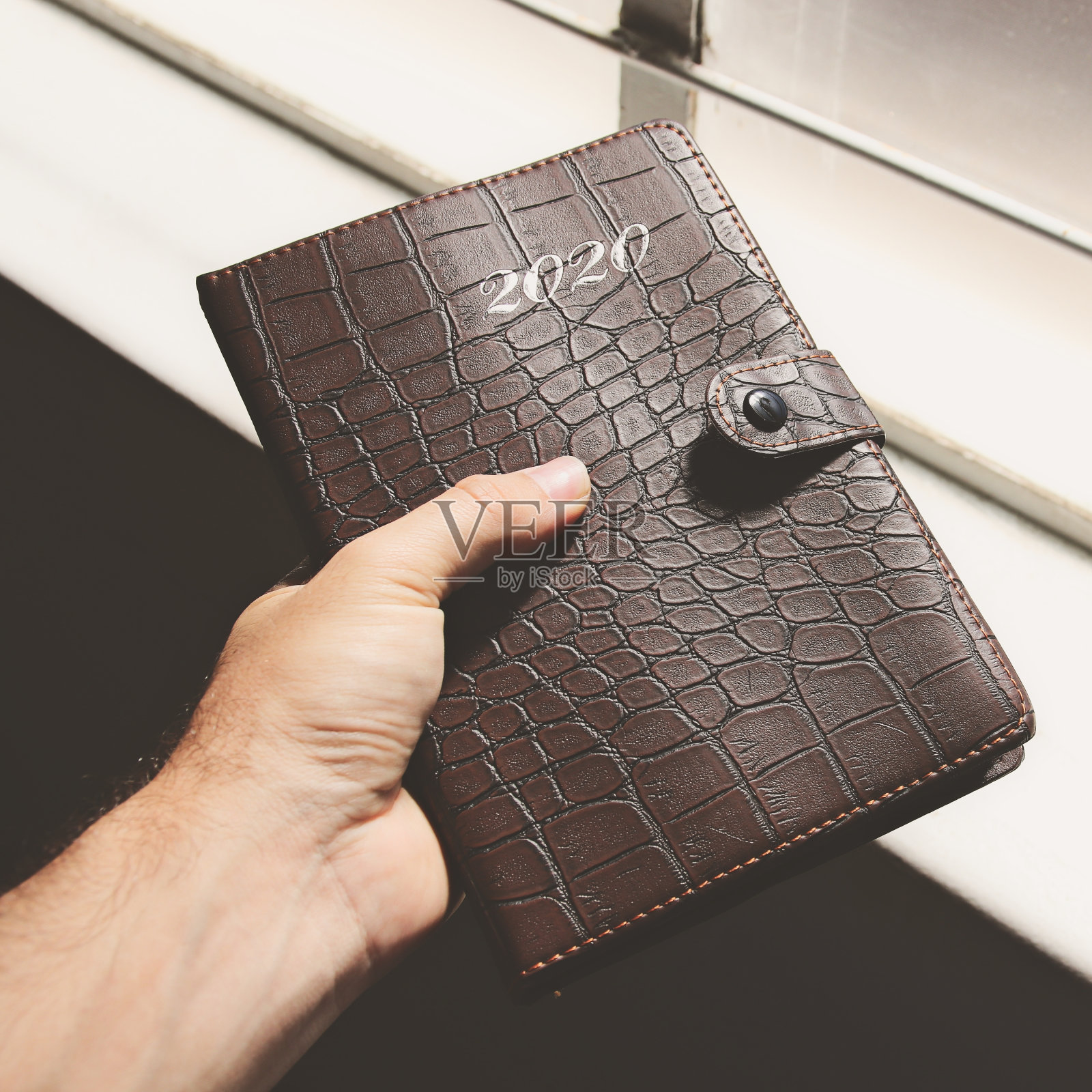 特写镜头，一只手拿着一个皮革封面的2020年计划照片摄影图片