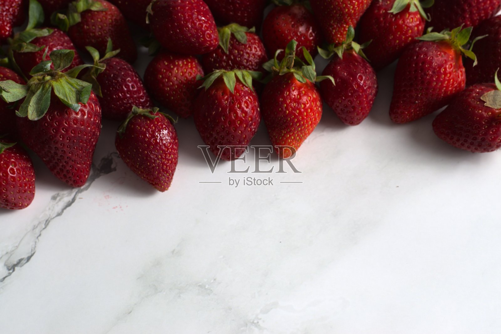 白色桌子上放着一串草莓照片摄影图片