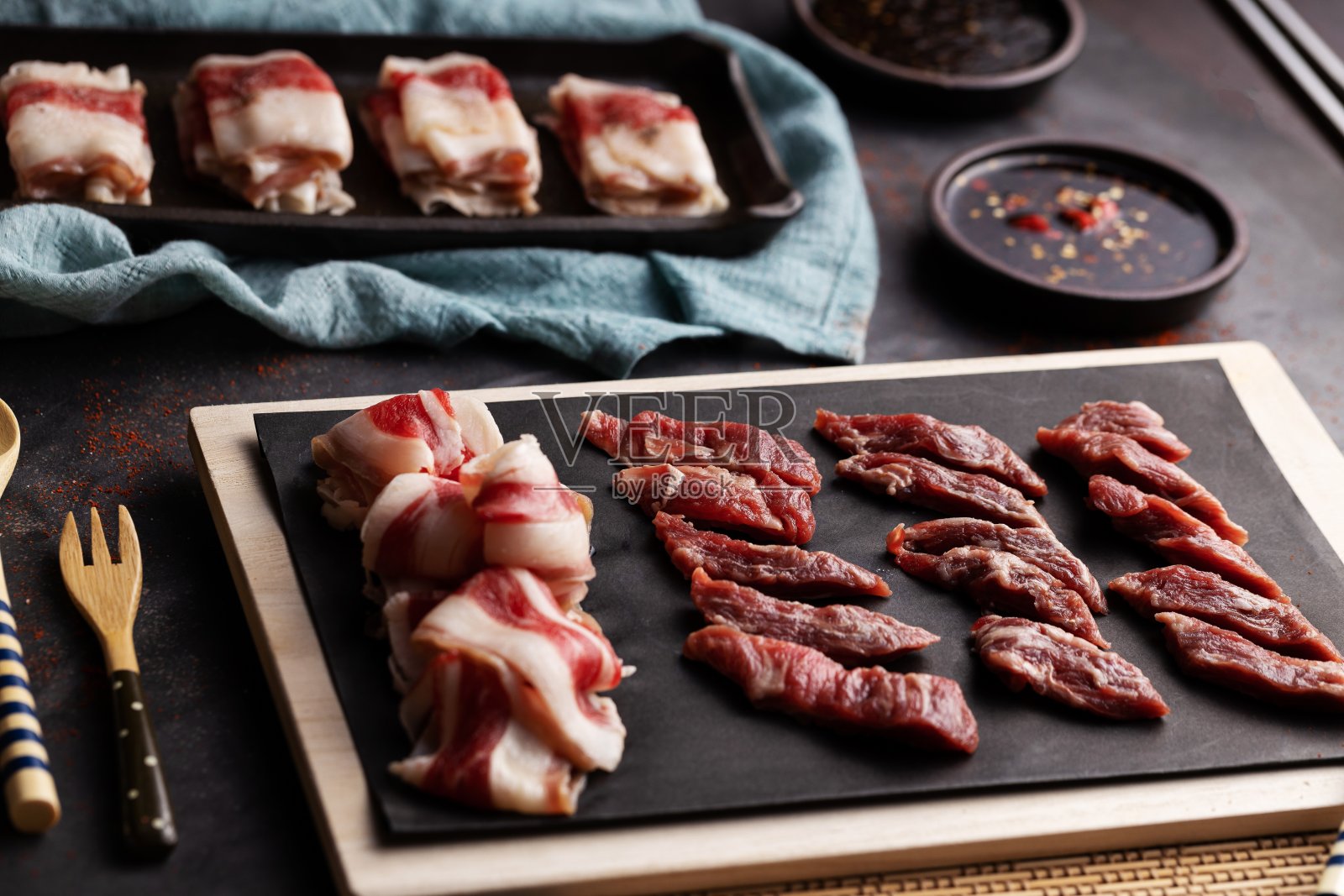 高角度拍摄的生肉片和盛在黑色托盘上的香料碗照片摄影图片