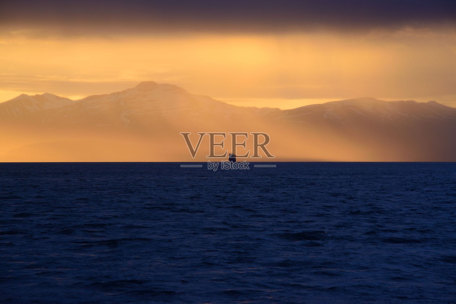 在冰岛的阿库雷里，明亮的金色日落天空在明亮的蓝色大海上照片摄影图片