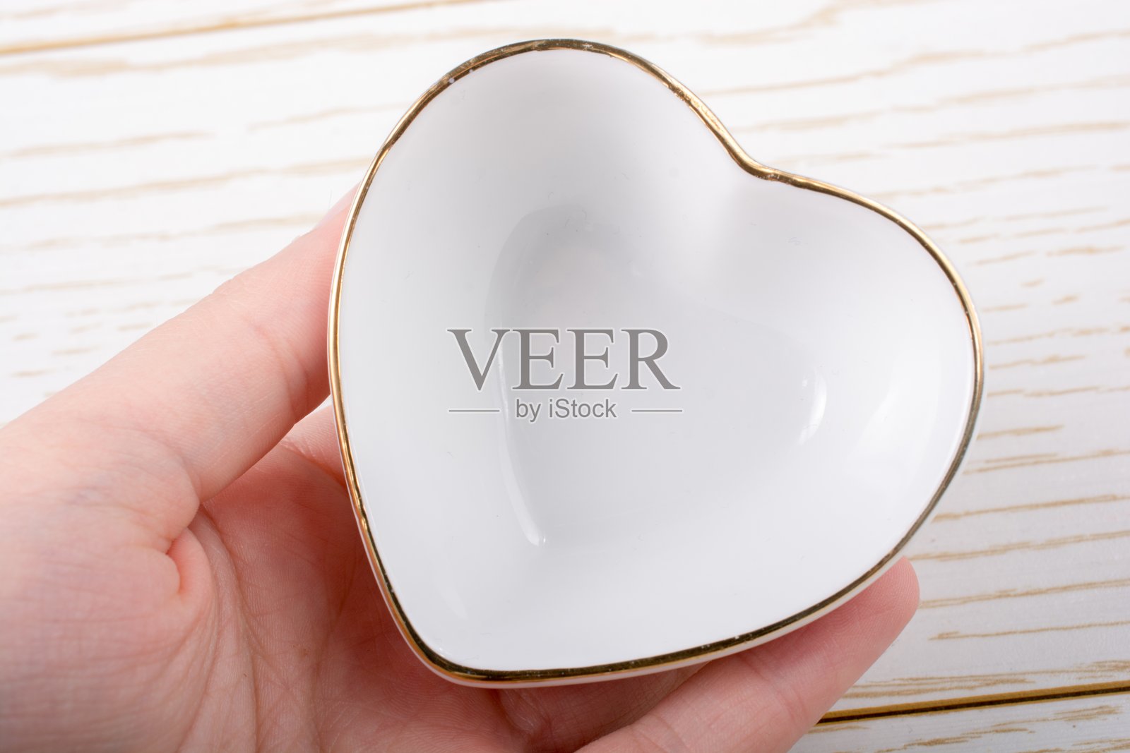 一个人手里的心形陶瓷小盘子的特写镜头照片摄影图片