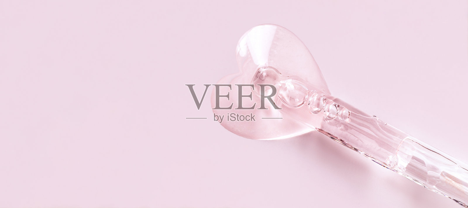 移液管上有粉色背景上心形的血清滴照片摄影图片