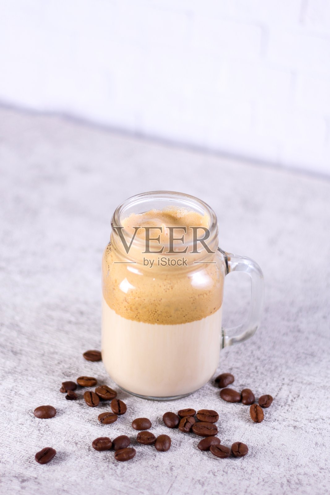 垂直拍摄的焦糖冰沙包围着桌上的咖啡豆照片摄影图片