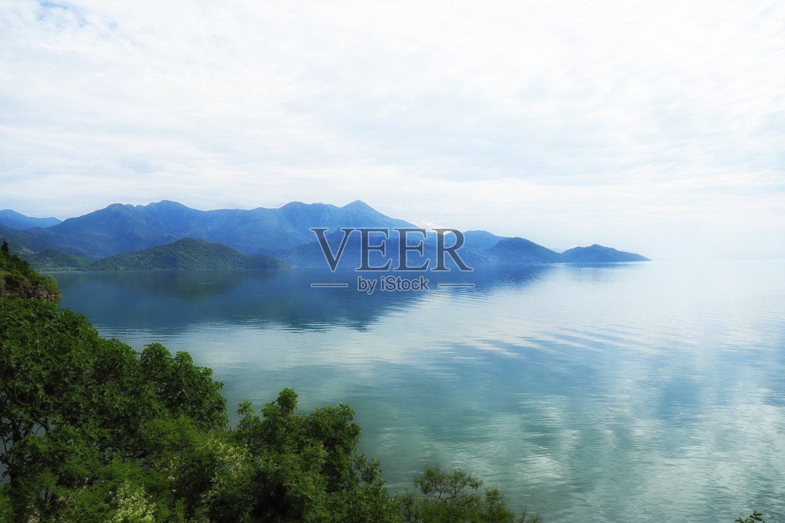 宁静的蓝色风景，有雾湖和山的背影照片摄影图片