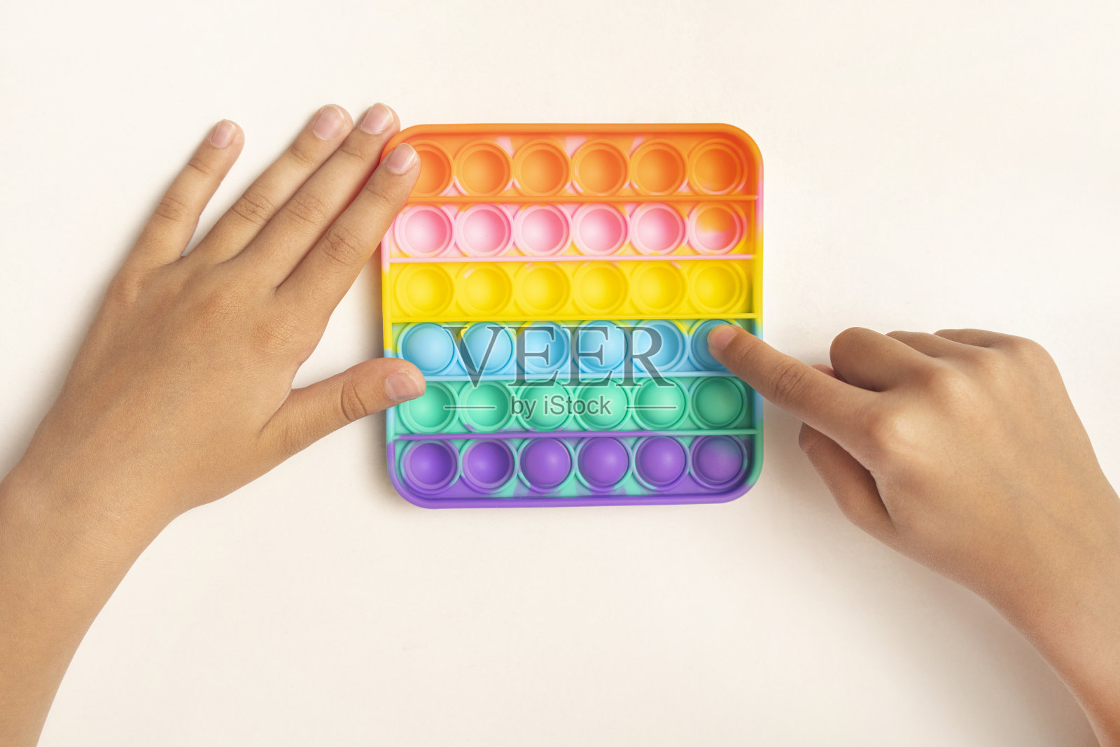 彩色的抗压力感官玩具指尖推弹出它在孩子的手中白色。孩子的发展观念。简单的酒窝游戏照片摄影图片