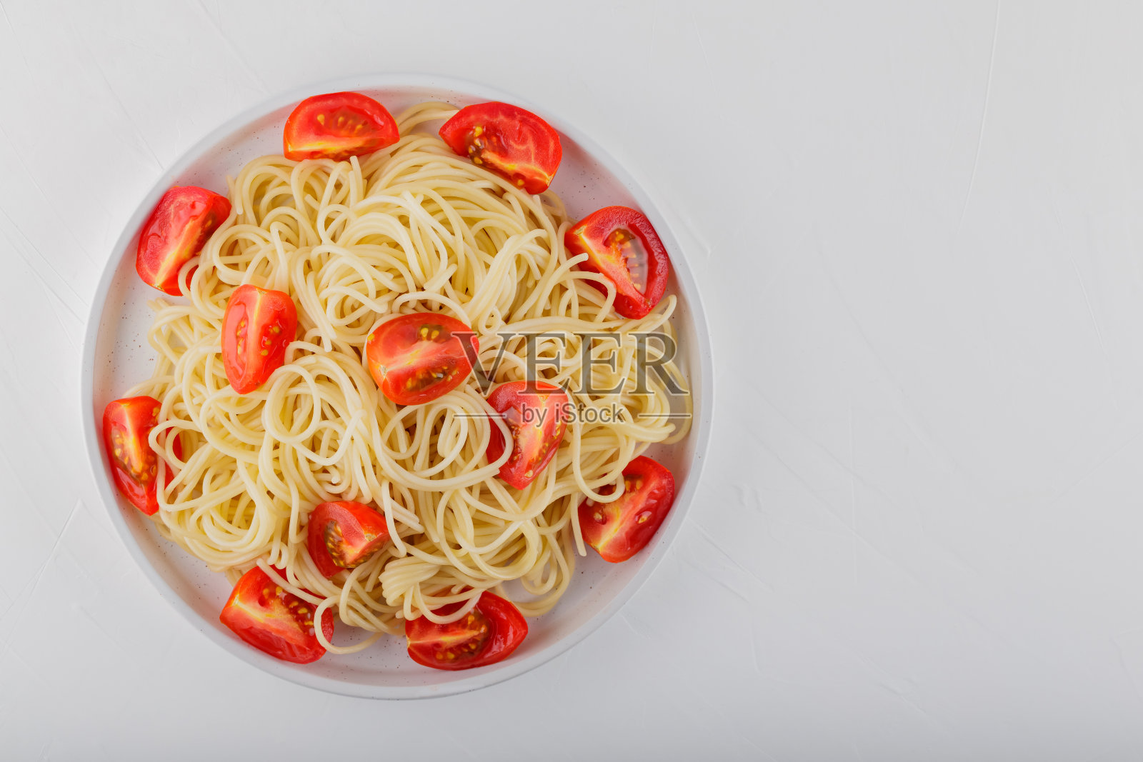 意大利面盘，樱桃番茄片在白色的背景。意大利面食和白盘子里的红番茄。前视图。本空间照片摄影图片