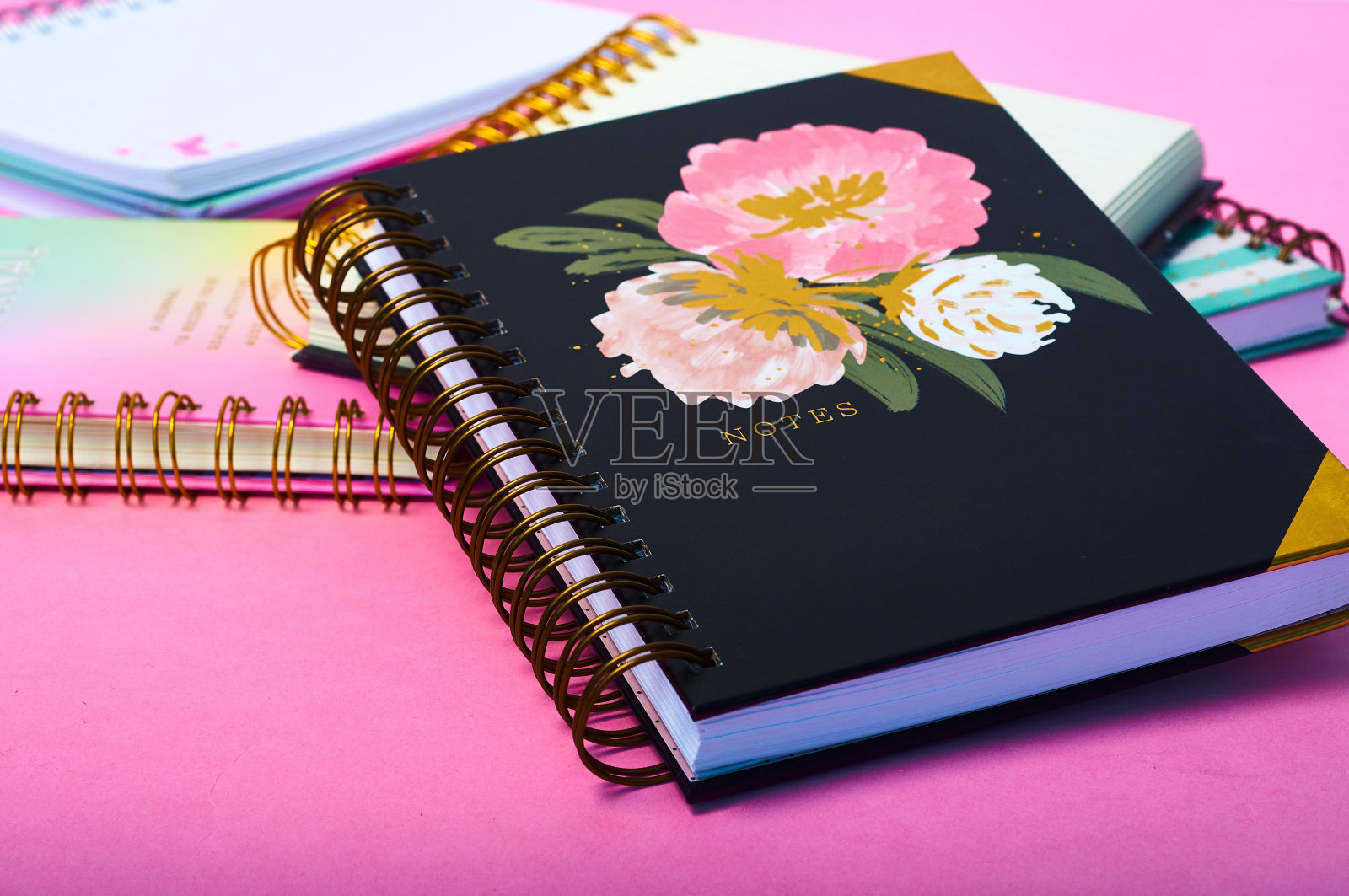 粉红色的桌子上有漂亮的设计的笔记本照片摄影图片