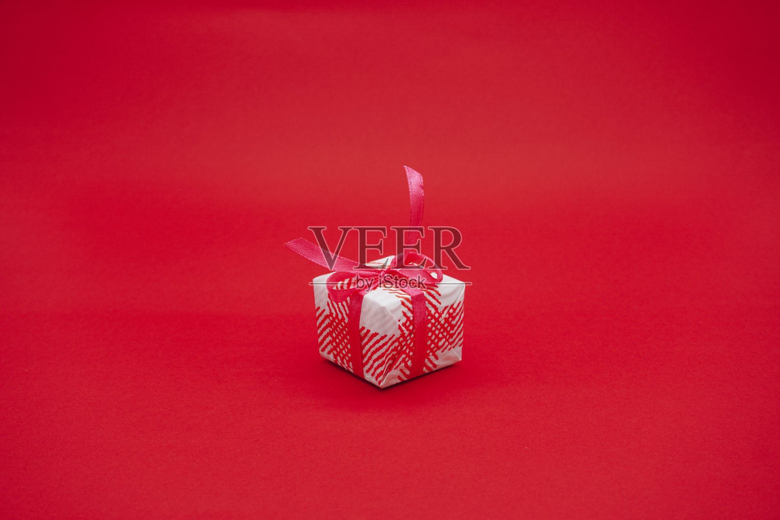 小白粉礼品盒与粉红色丝带。圣诞礼物盒子。孤立在红色背景上照片摄影图片