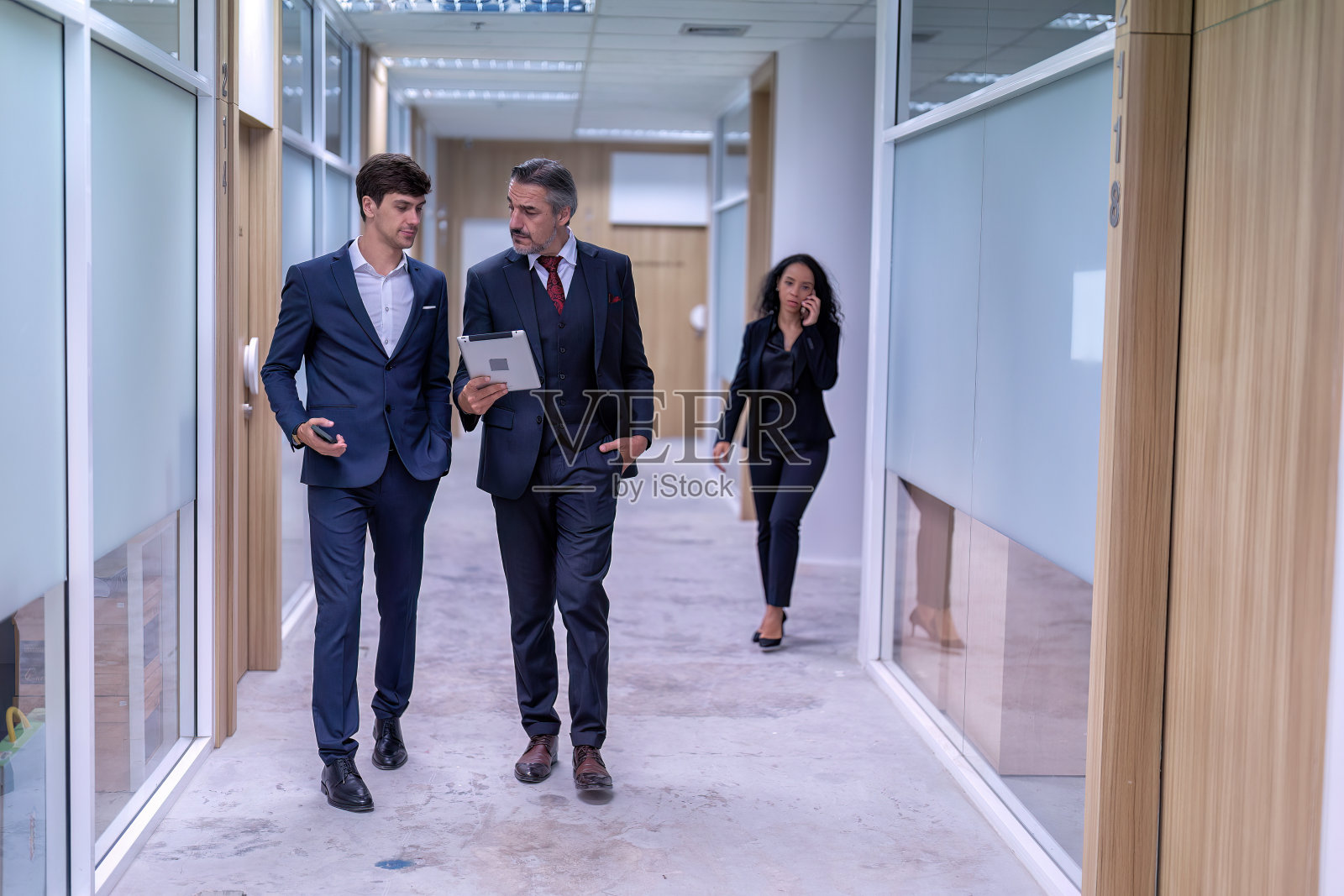 高级员工经理和工程师一起走在办公室的走道上照片摄影图片