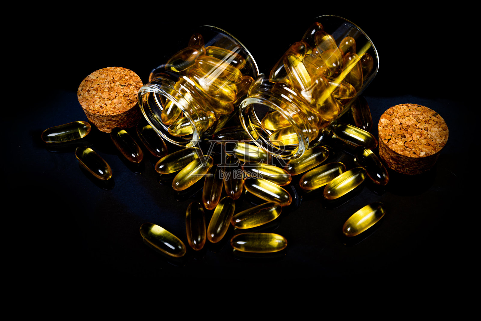 鱼油胶囊。黄色的欧米茄3药丸在瓶子上就黑黑的。葡萄酒杯装鱼油胶囊。在jar。在桶安瓶照片摄影图片