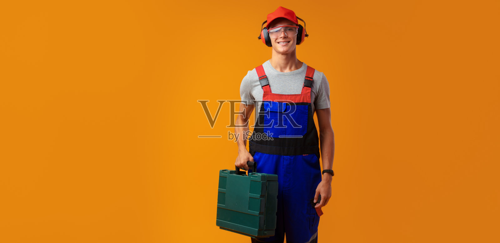 年轻工头的肖像与工具箱在黄色的背景照片摄影图片