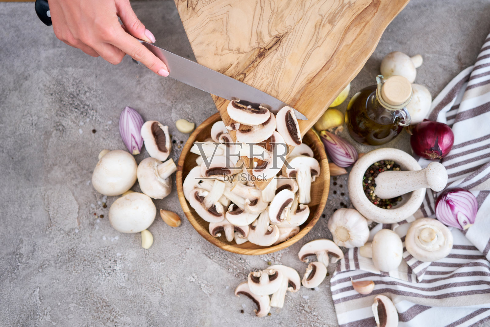 一名妇女正在把切好的香菇倒进家庭厨房的木碗里照片摄影图片