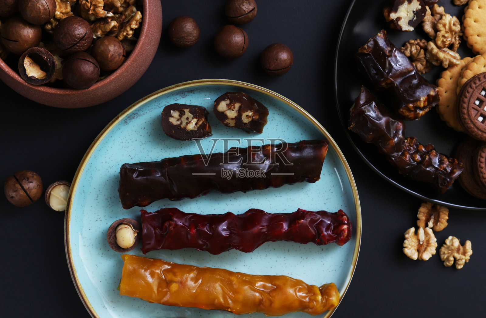 churkhela是一种甜甜的美味，用坚果和面粉制成的浓稠果汁。格鲁吉亚教堂的希拉放在盘子里，放在深色的桌子上，还有坚果。特写镜头照片摄影图片