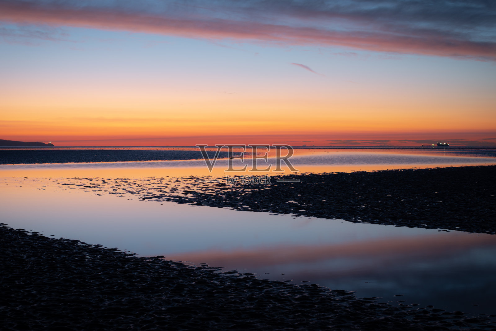 退潮时可以看到远处的船只和灯塔照片摄影图片