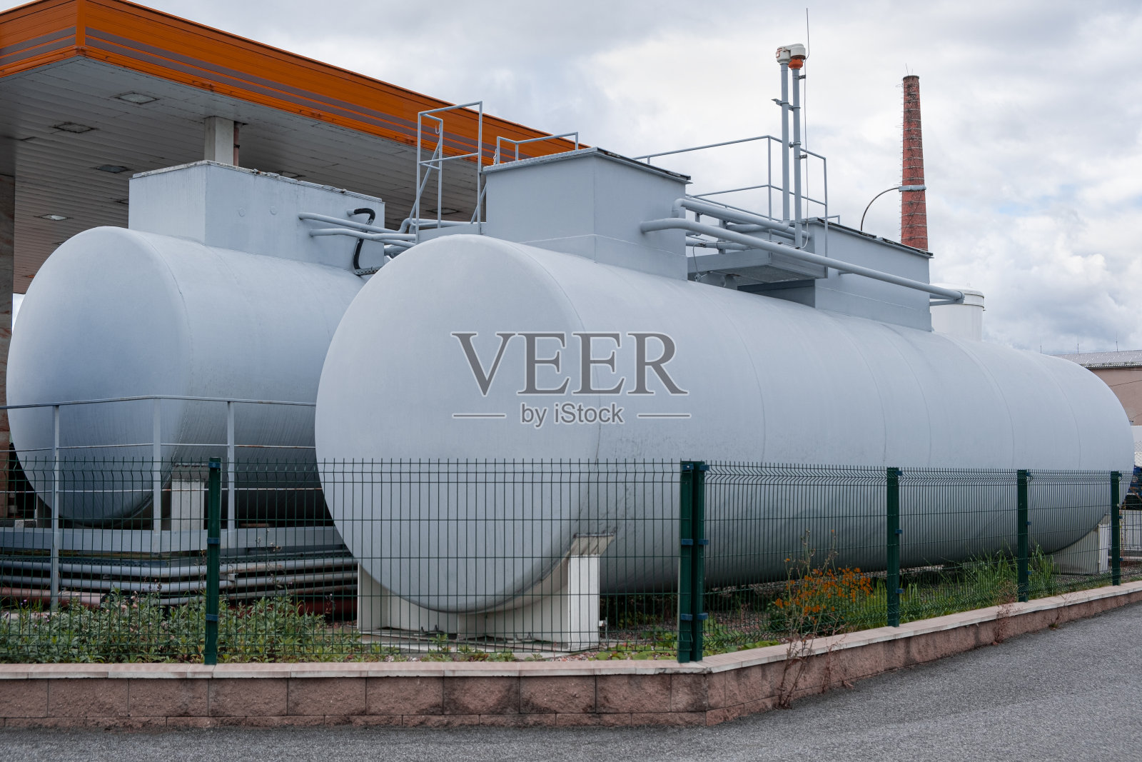 卧式圆柱形储气罐容器巡视。油站上的灰色室外储油罐照片摄影图片