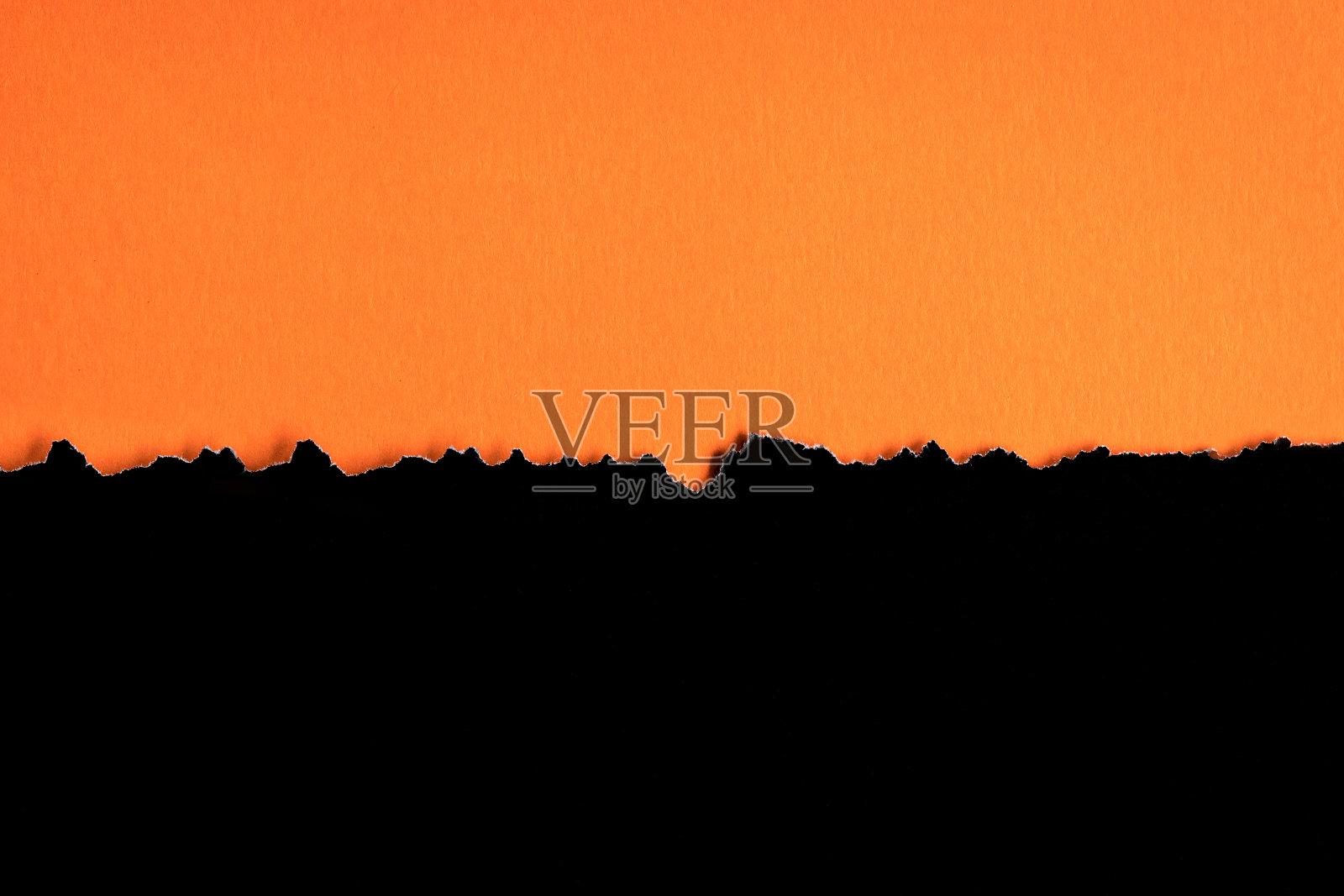 撕掉的半张黑色纸水平放在橙色纸的底部。照片摄影图片