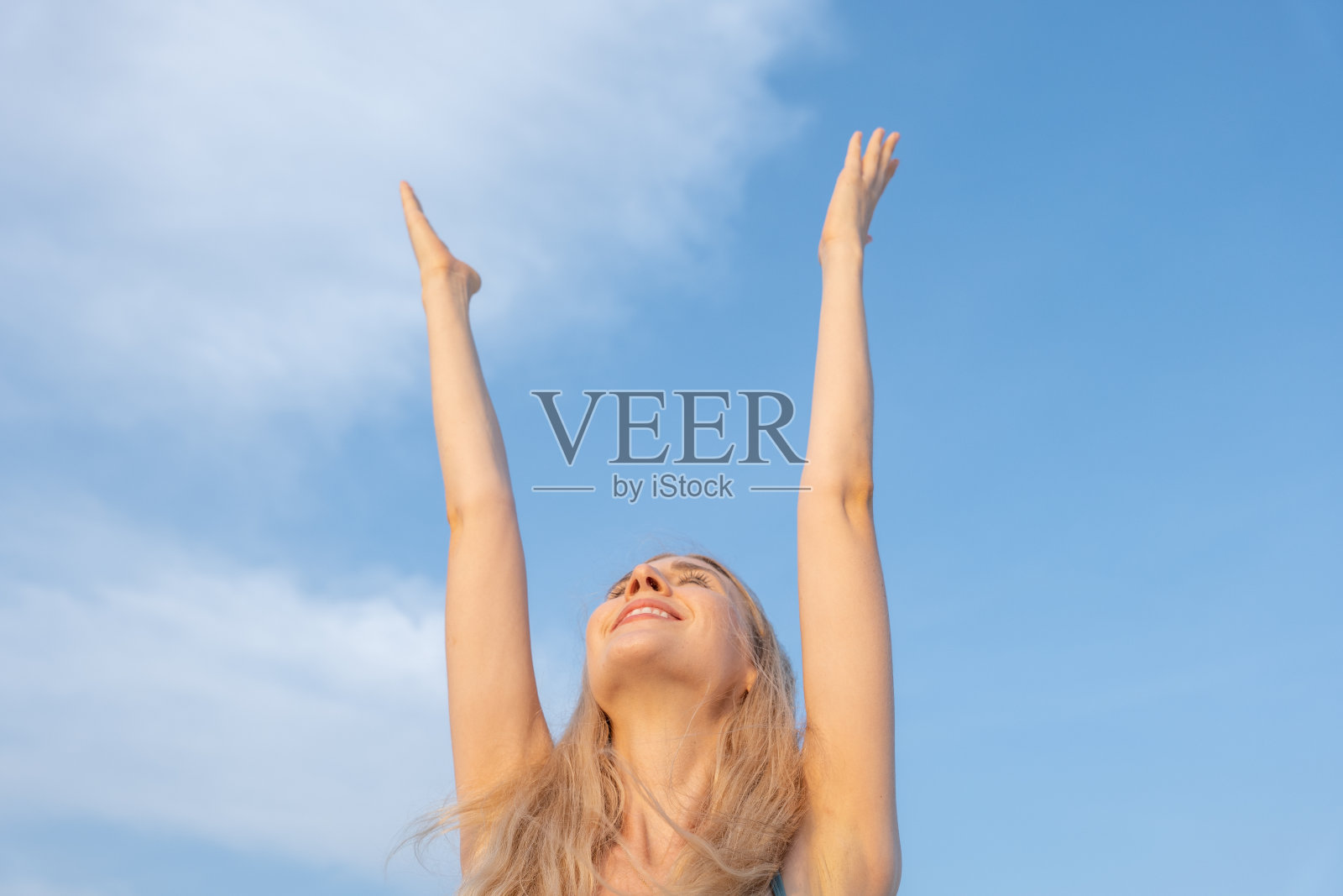 日落时分，年轻女子站在屋顶上，手臂高举照片摄影图片