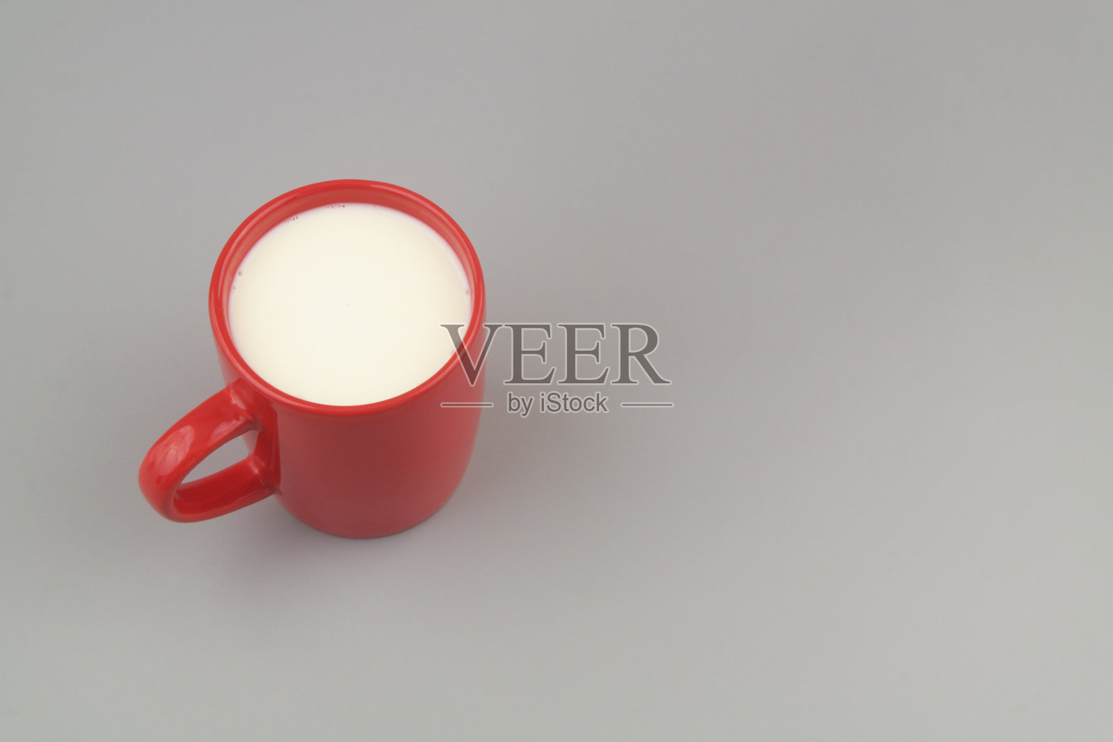 红色杯牛奶或奶油在灰色背景与复制空间。照片摄影图片
