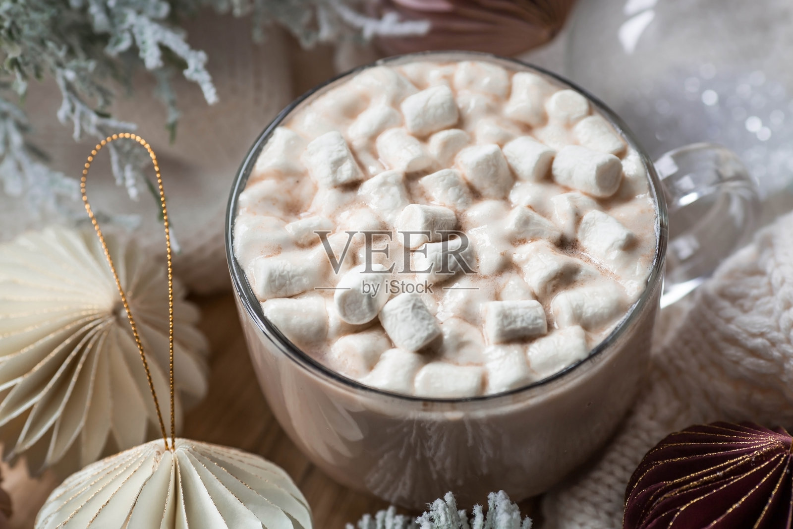 时髦的纸圣诞树玩具和一个玻璃与热巧克力，棉花糖在木制背景。米色色调。从上面看。横幅设计，网页。照片摄影图片