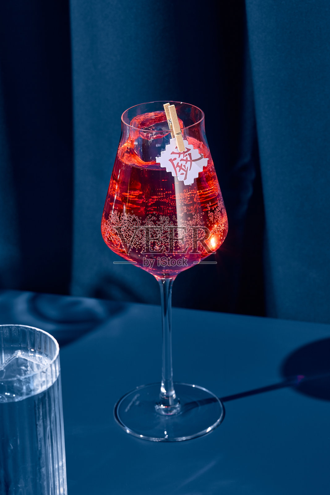 优雅的鸡尾酒与红色苦艾酒在蓝色背景与阴影。潮流风格的彩色背景苦艾酒鸡尾酒。当代概念的酒精饮料。酒保鸡尾酒。照片摄影图片