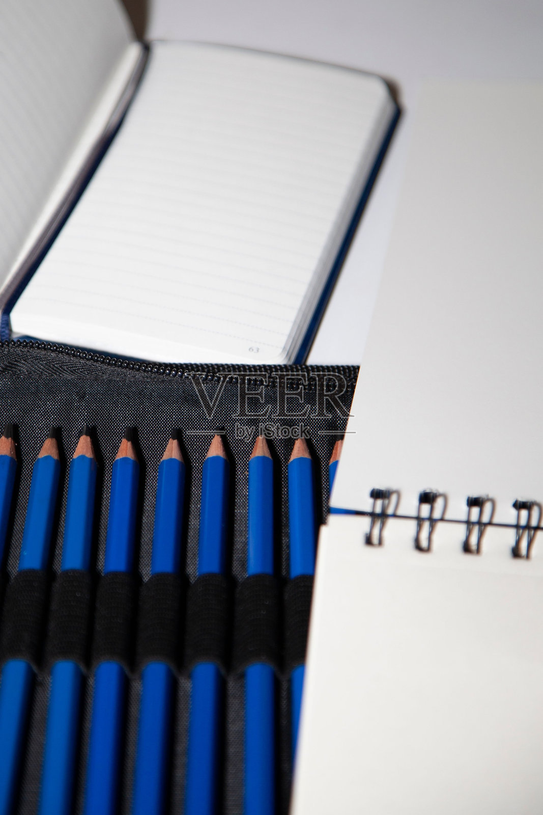 垂直拍摄的蓝色炭笔在一个黑色的情况下，旁边打开的书和素描本照片摄影图片