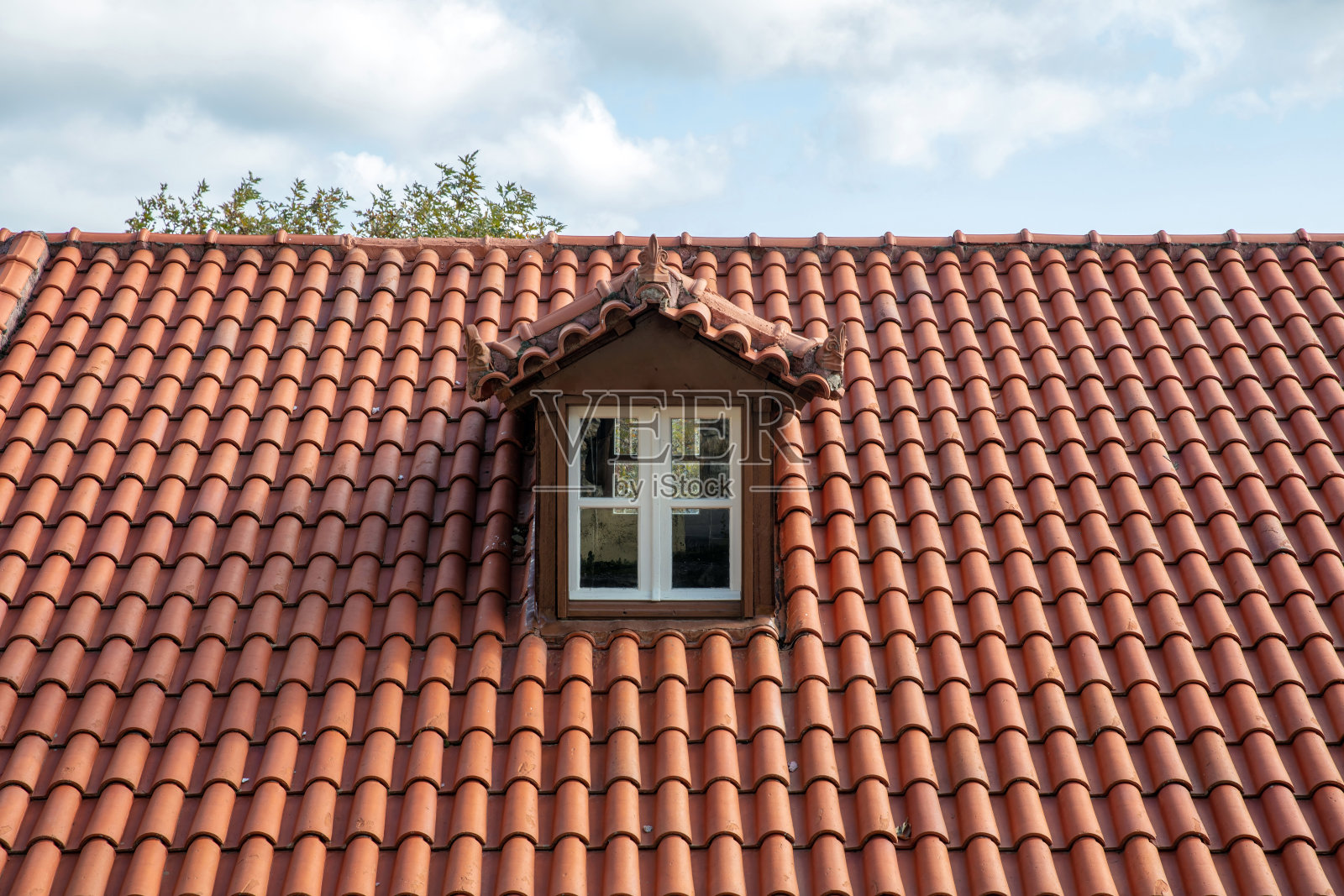 红瓦屋顶和阁楼。顶楼、屋顶上的多马窗呈白色。照片摄影图片