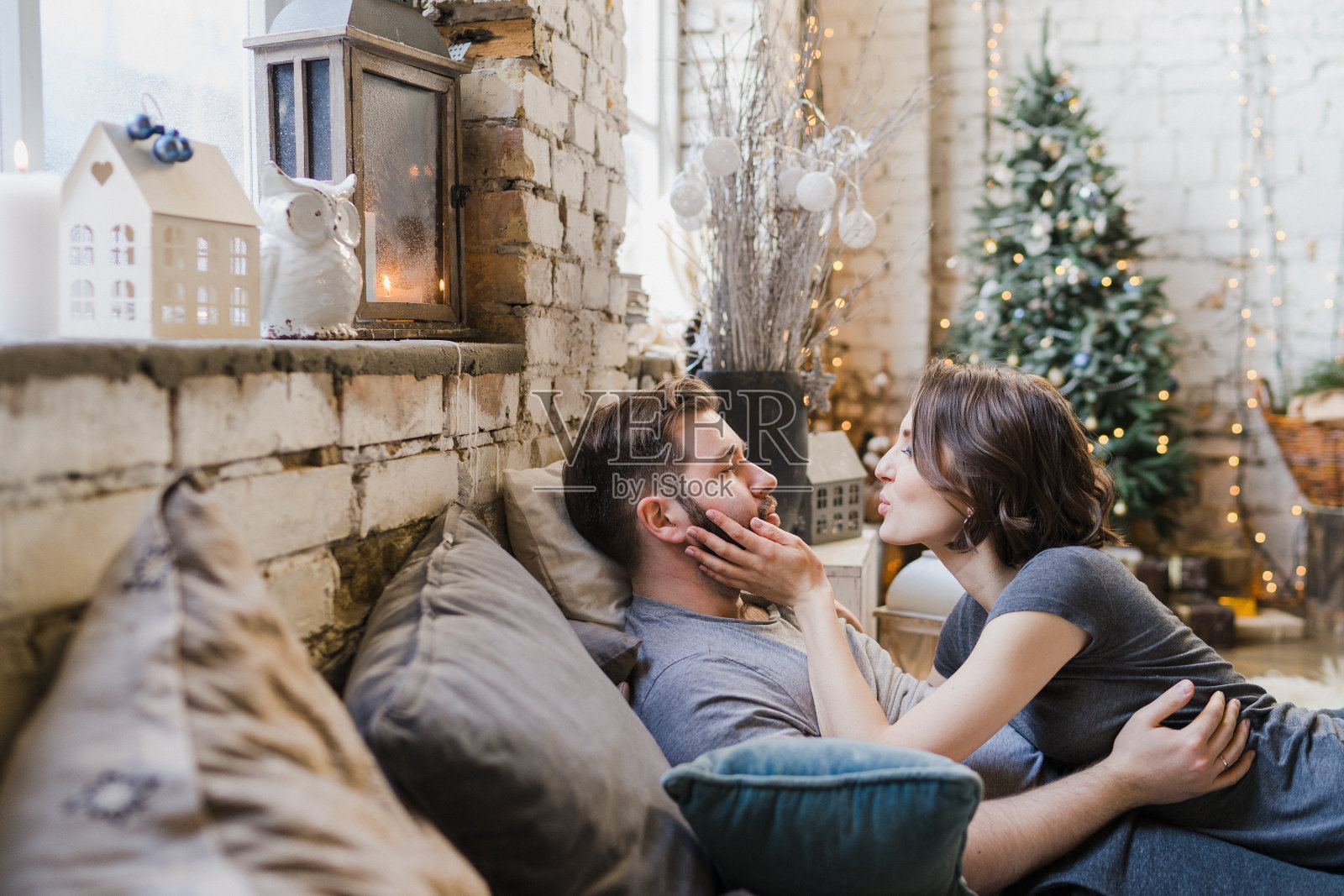 冬天的周末在家。年轻的白人夫妇穿着舒适的衣服在床上拥抱。照片摄影图片