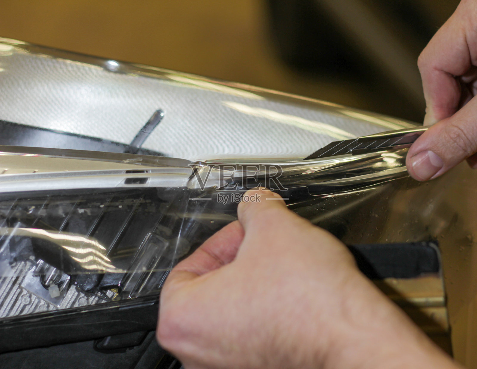 特写显示的过程安装PPF的前大灯。照片摄影图片