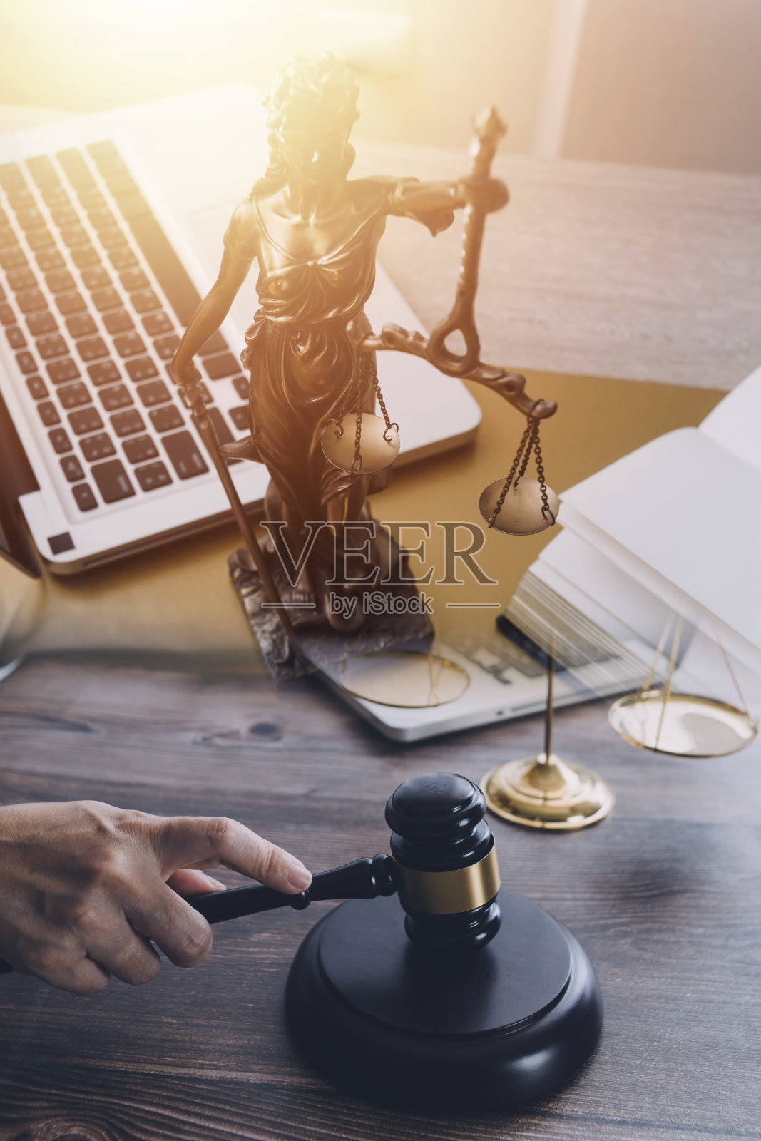 正义与法律观念。男法官在法庭上拿着木槌，用电脑和键盘对接，戴着眼镜，在晨光中坐在桌子上照片摄影图片