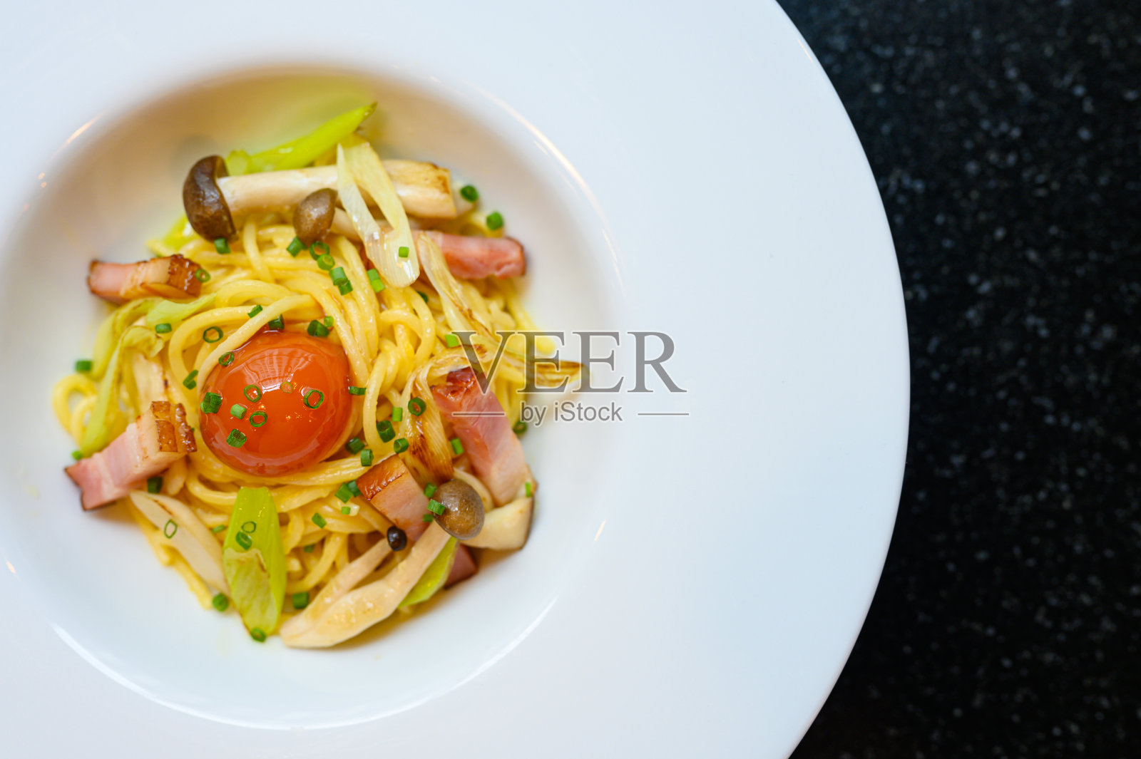 熏五花肉和二鬓菇放在白色的盘子里。隔离在黑色背景。照片摄影图片