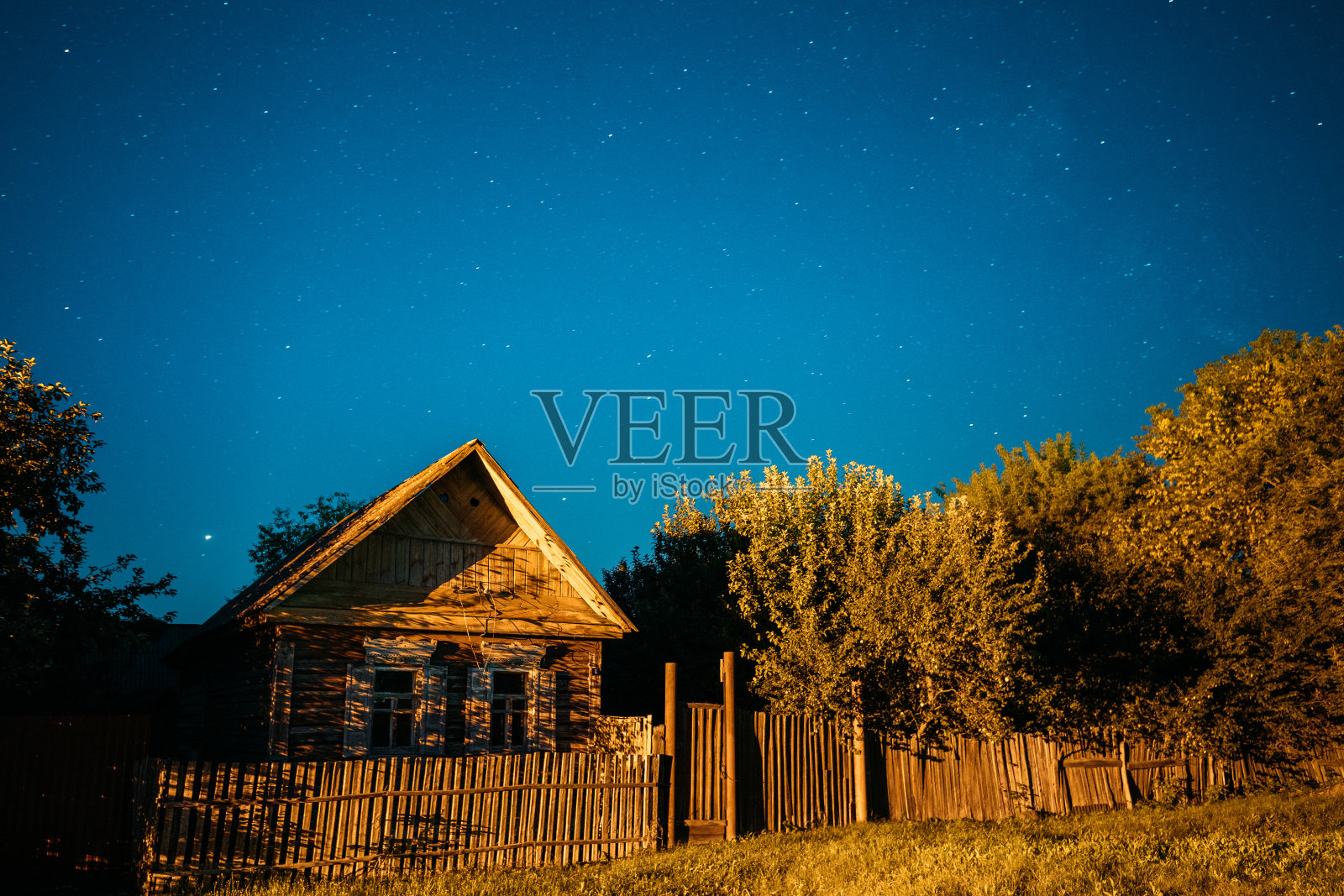 村子里老房子的夜空。夜晚，房子上面的星空，明亮的星星和流星的轨迹。夏日大自然上空闪烁的星星照片摄影图片
