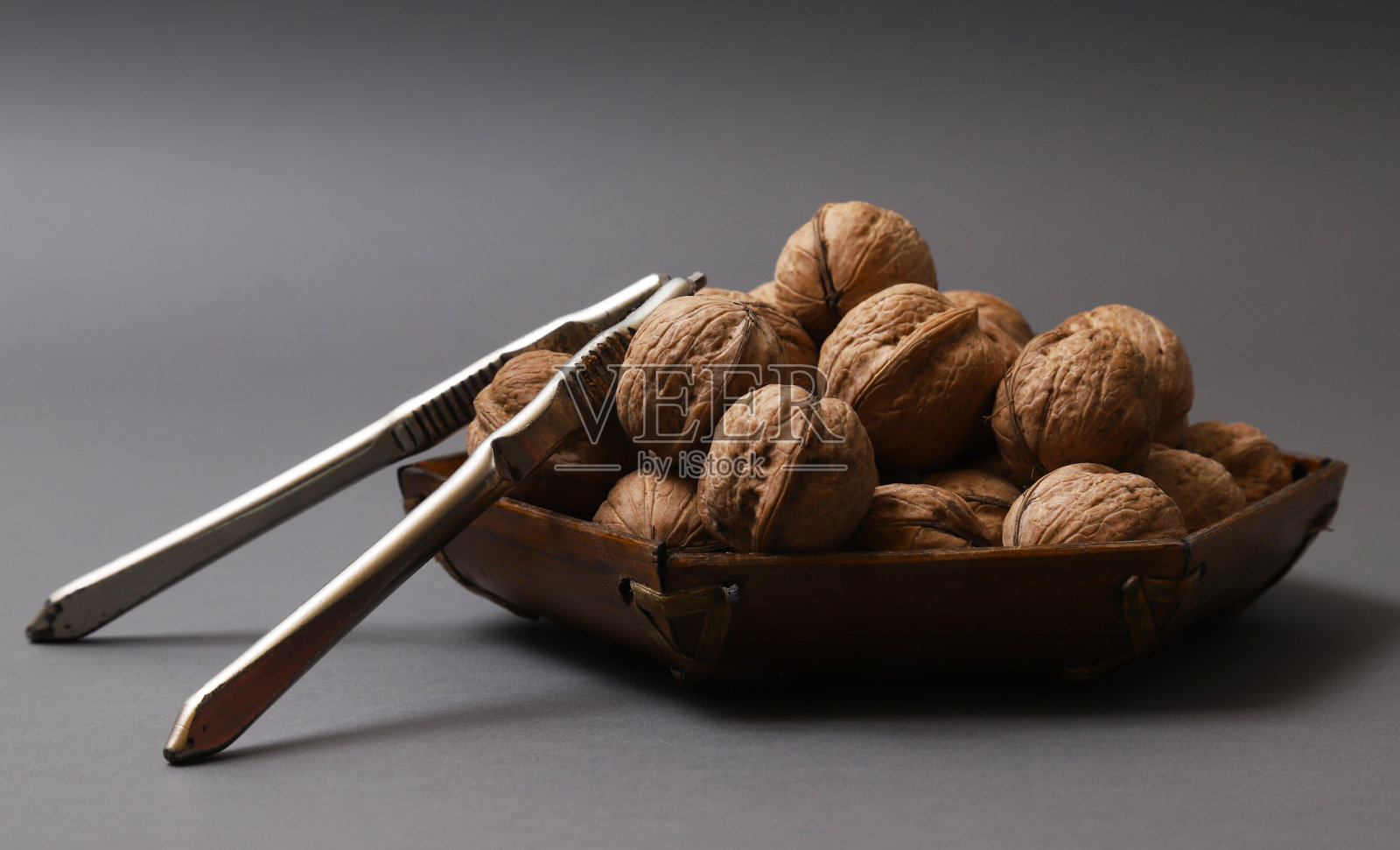 胡桃放在木碗里，还有胡桃夹子。浅景深照片摄影图片