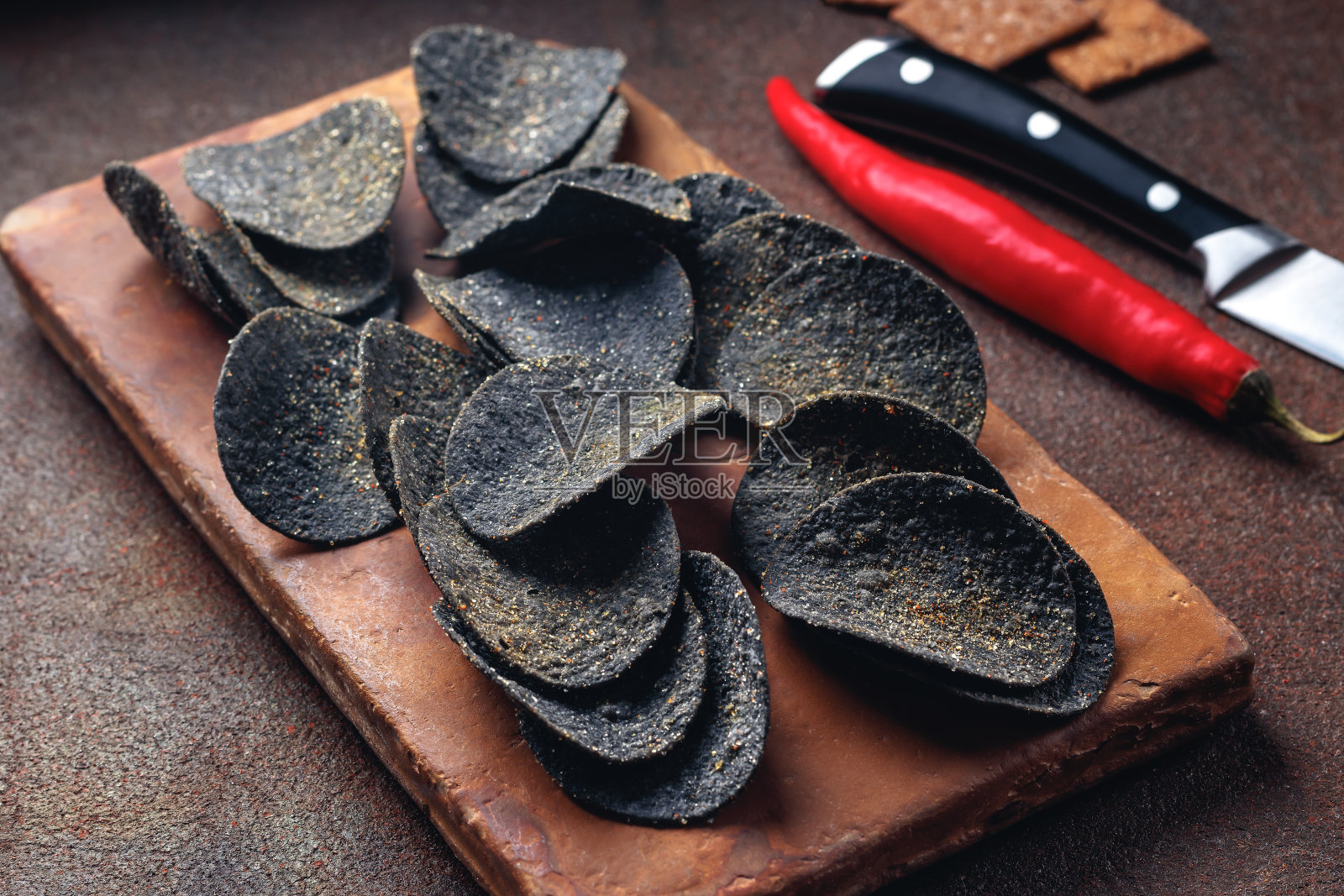 黑薯片放在石头盘子里。黑色食品照片摄影图片