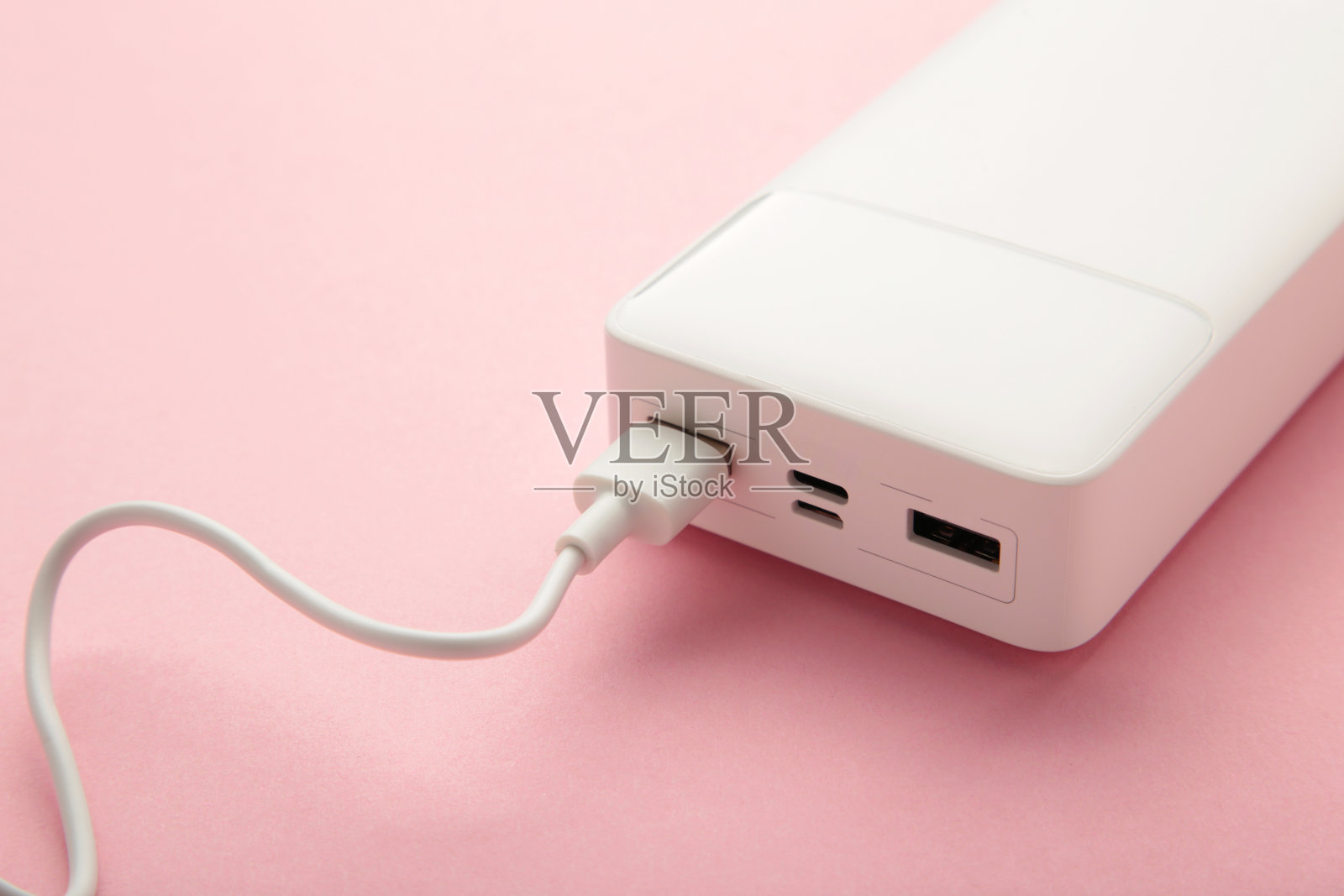 粉色背景的usb连接线便携式充电宝。照片摄影图片
