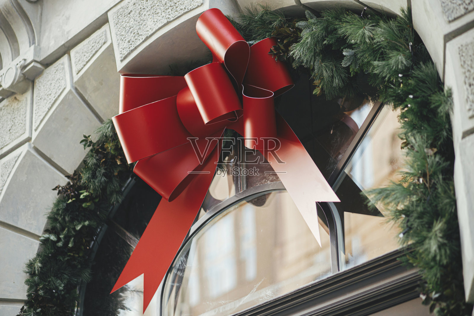 时尚的圣诞大弓和杉木树枝的建筑外观。城市街道上的现代圣诞装饰。在欧洲度寒假。圣诞快乐照片摄影图片